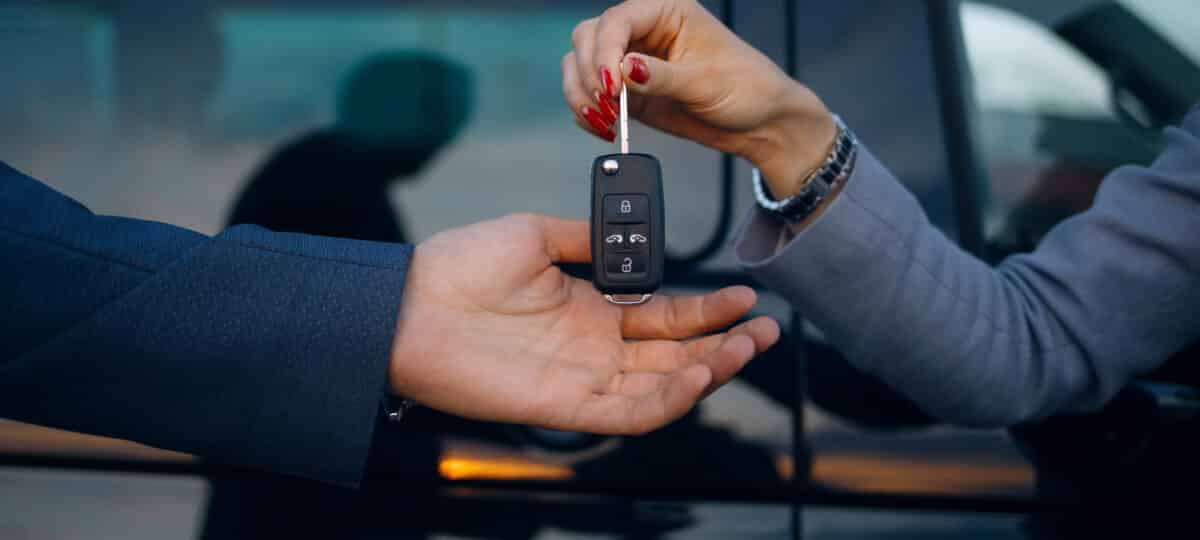 Woman give cars key to man. Hands hold car keys. Car rental