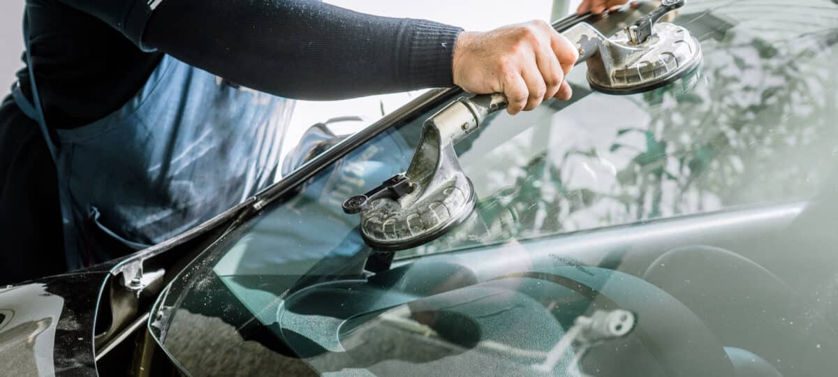 Mechanic man changing the broken windshield